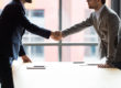 Two businessmen shaking hands at meeting, making agreement