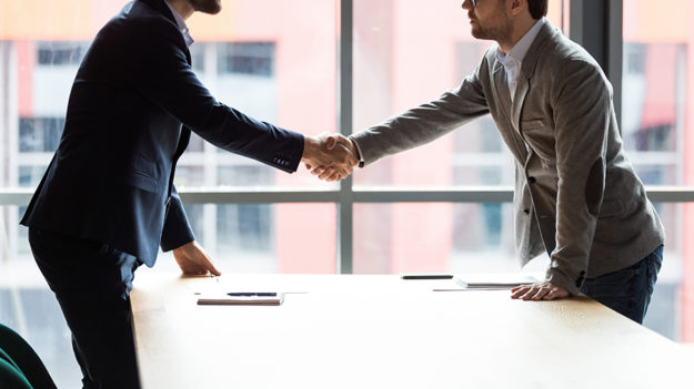 Two businessmen shaking hands at meeting, making agreement Two businessmen shaking hands at meeting, making agreement