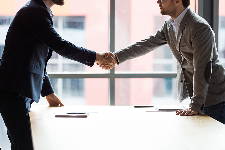 Two businessmen shaking hands at meeting, making agreement Two businessmen shaking hands at meeting, making agreement