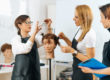 Hairdressers Training with Mannequin Head in Education Center. Professional female hairdresser teaching adult students haircutting technique.